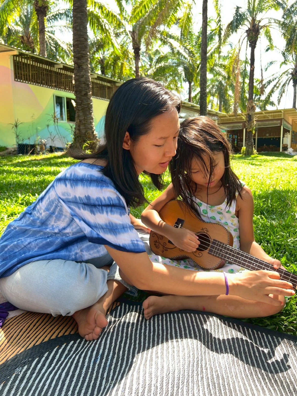 Teacher giving a one-on-one ukulele lesson to a child outdoors at Bamboo Valley