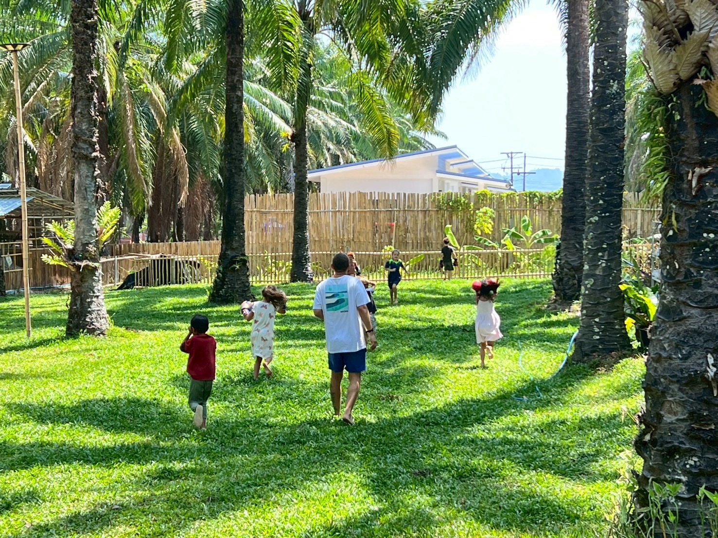 Children running freely on grass among palm trees at Bamboo Valley