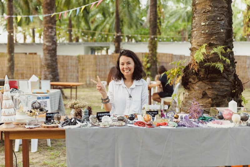 A stallholder smiles behind her table of crystals and decorations