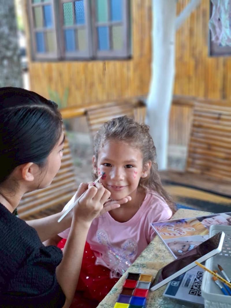 A girl smiles while her face is painted