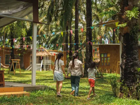 A teacher walking hand in hand with three girls across the lawn under the bunting