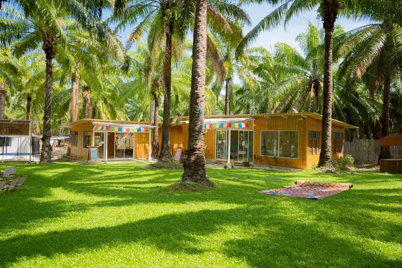 Bamboo classrooms with bunting across a green lawn under tall palms