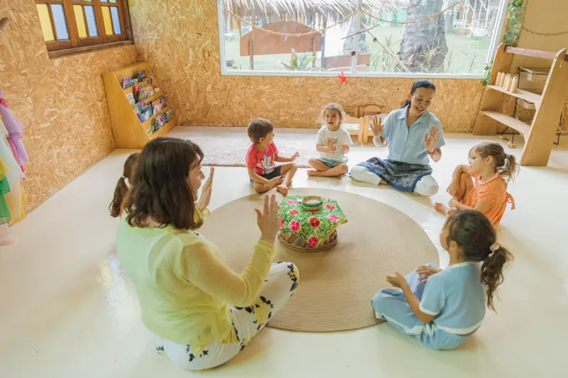 A teacher leading a clapping circle on a round carpet