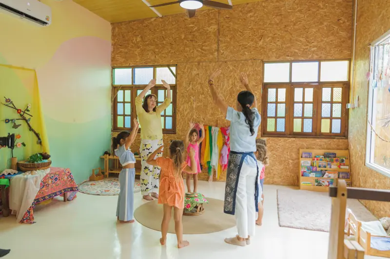 Teachers and children moving together in a pastel classroom