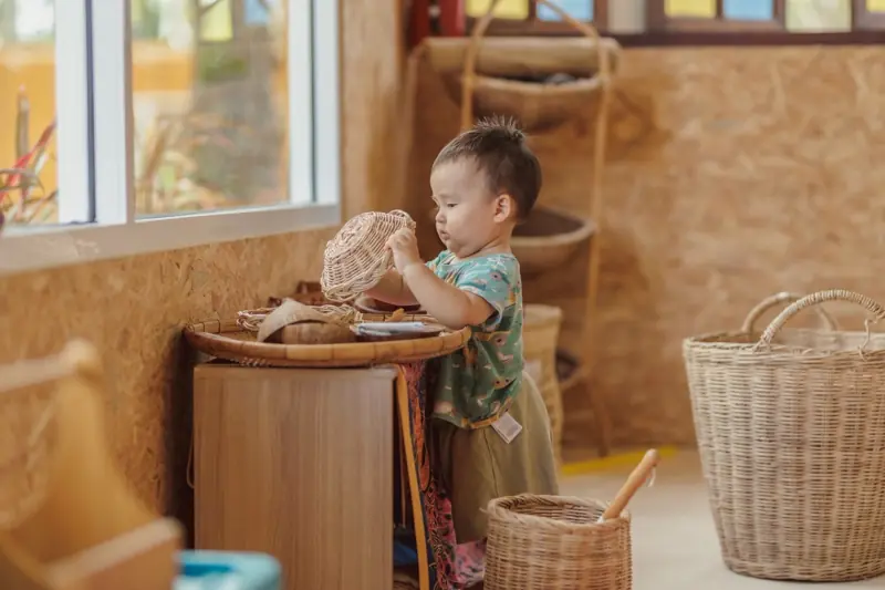 A toddler exploring a woven basket by a bright window