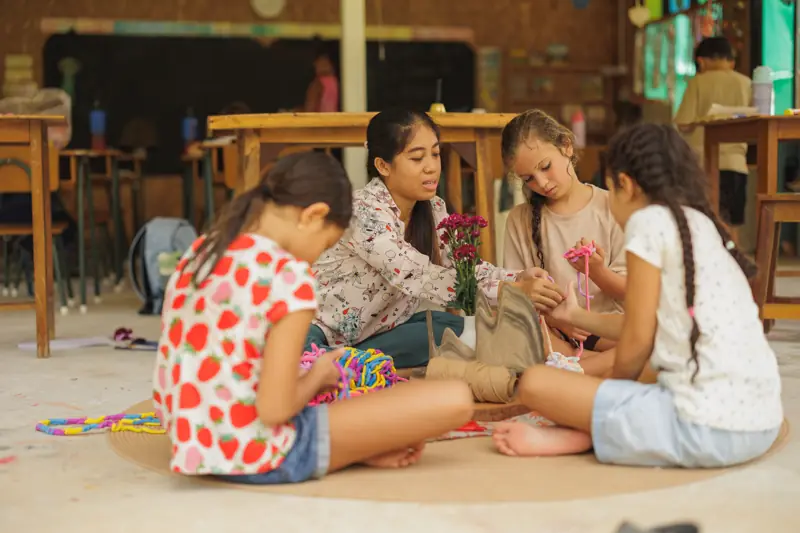 A teacher and three girls working together on the classroom floor