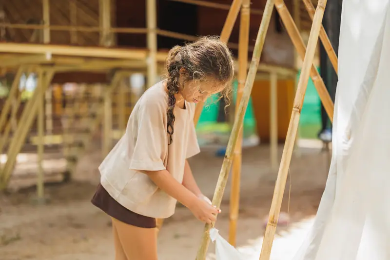 A girl lashing bamboo poles together for a fort