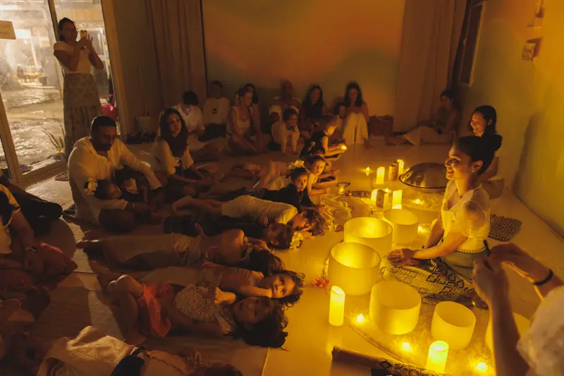 Families lying together at a candlelit sound-healing evening