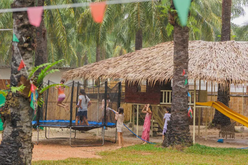 A child in mid-air on the trampoline in front of the thatched pavilion