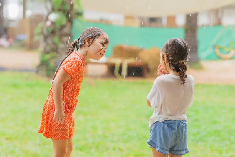 Two girls laughing during water play on the lawn